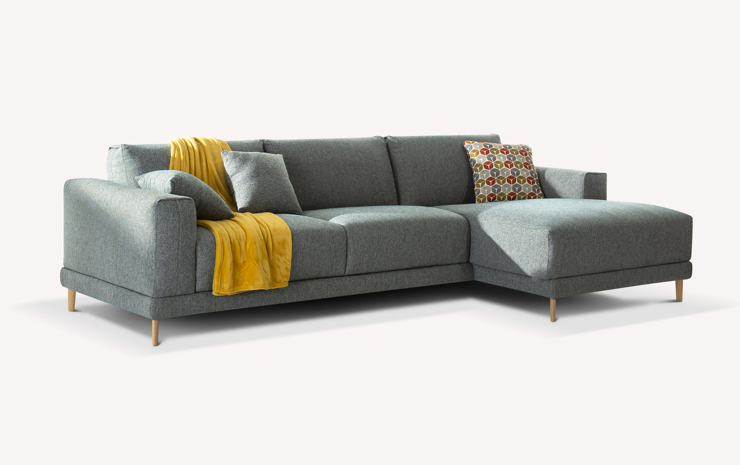Canapé d'angle en tissu gris avec coussin à motifs et plaid jaune, vu de trois quarts