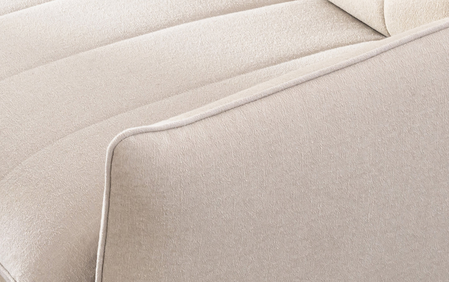 Zoom sur l'accoudoir d'un canapé convertible Dita en tissu fluf beige, montrant la revêtement douce et les coutures précises