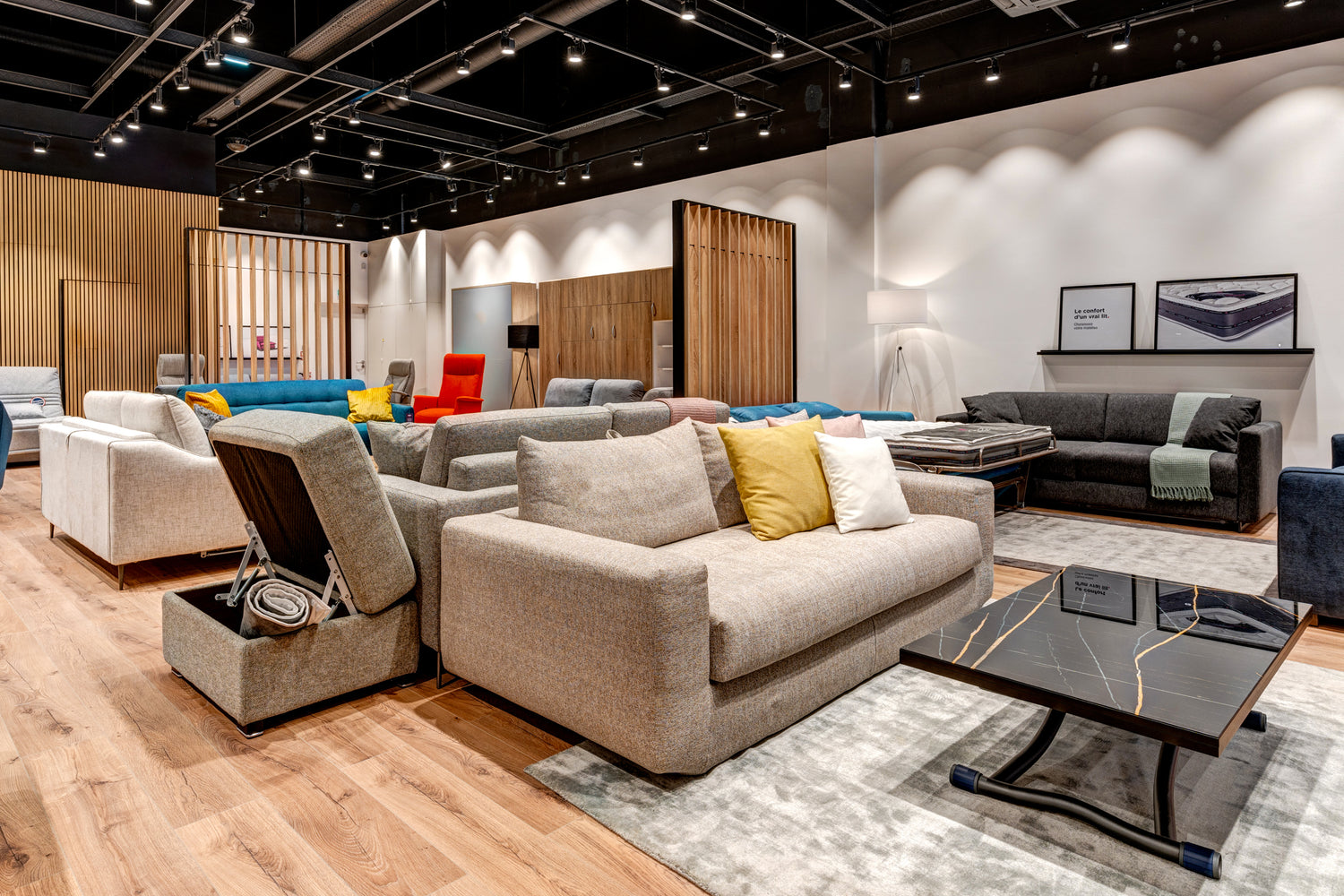 Showroom de La Maison du Convertible avec divers canapés convertibles et fauteuils colorés, éclairage moderne et parquet en bois clair