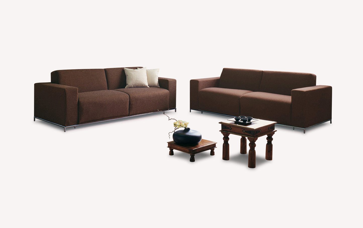 Canapés convertibles en tissu marron avec coussins, accompagnés de tables en bois et d'un vase décoratif