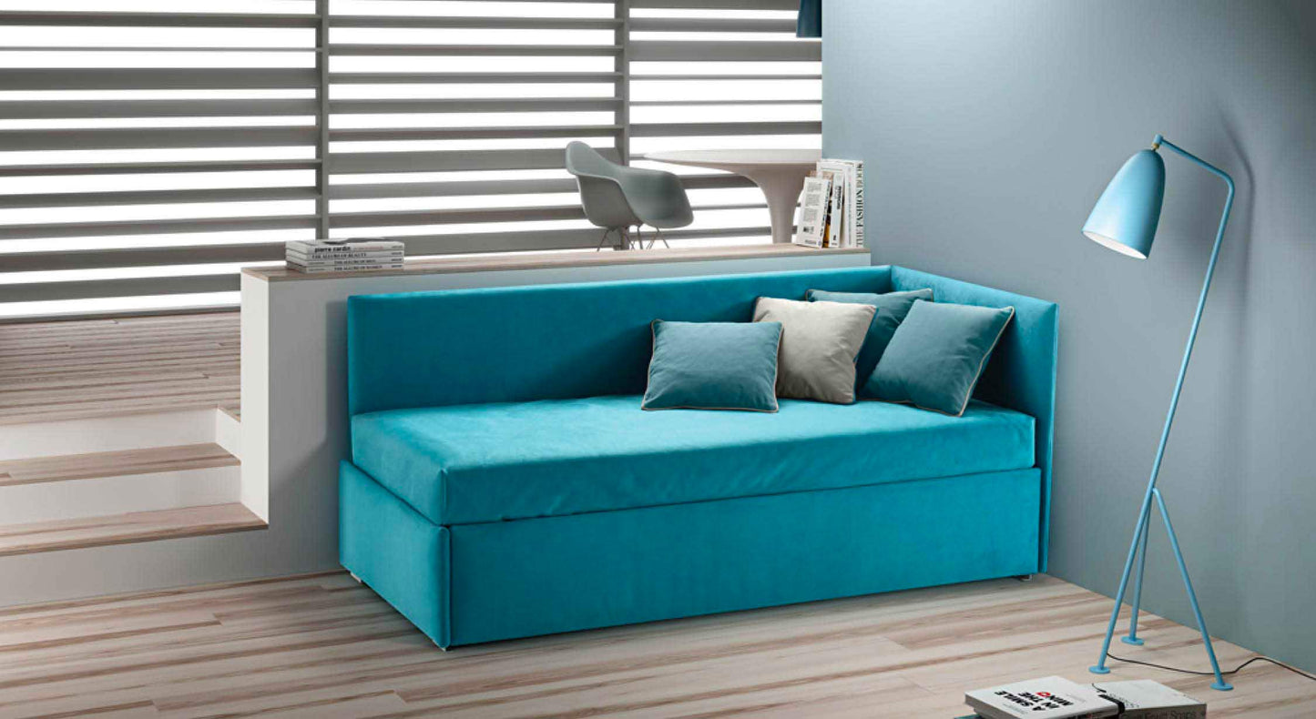 Lit gigogne bleu avec coussins, situé dans un coin moderne et épuré, éclairé par une lampe sur pied assortie