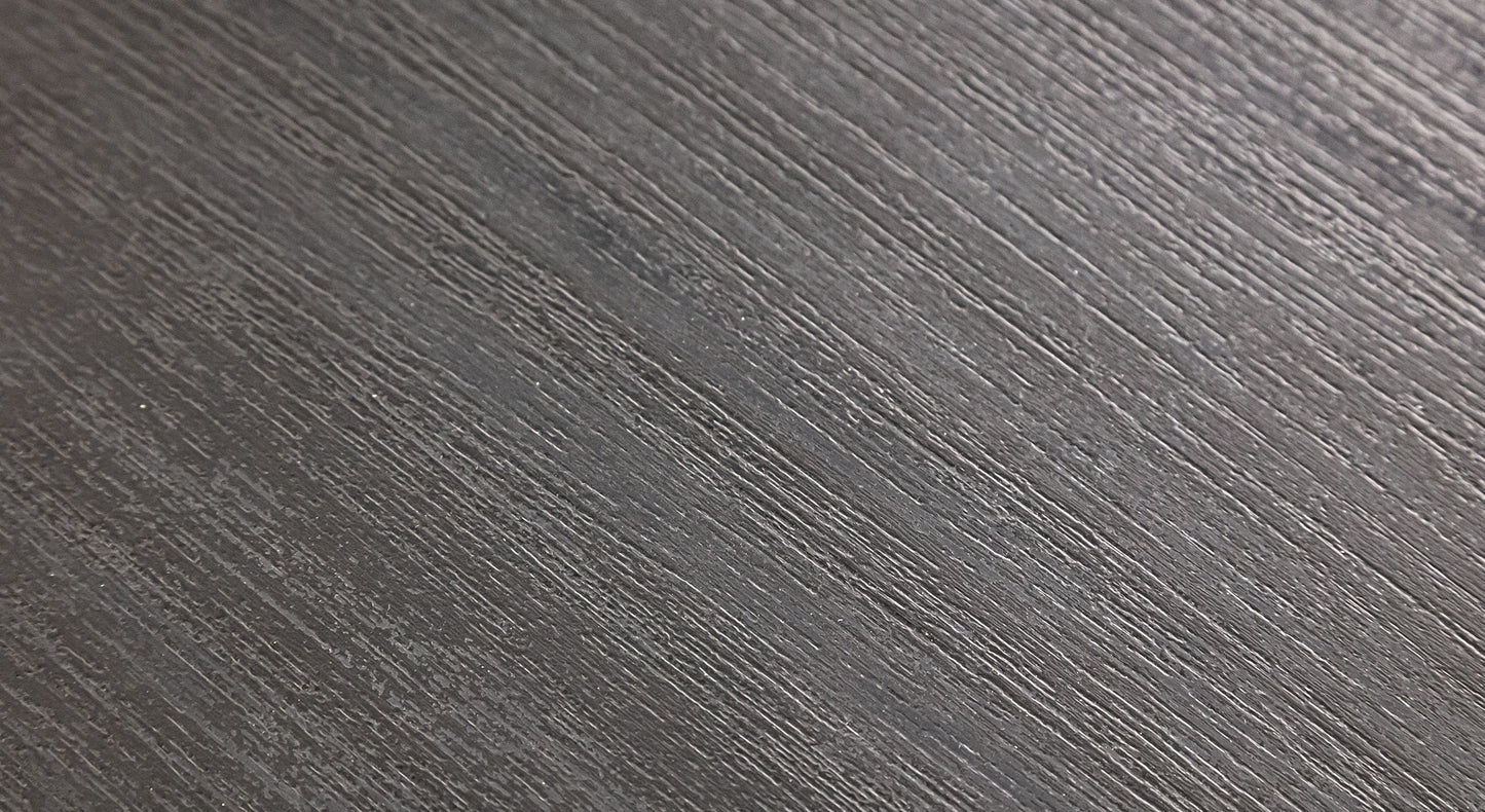 Surface texturée gris foncé avec des stries parallèles, évoquant un matériau moderne et élégant