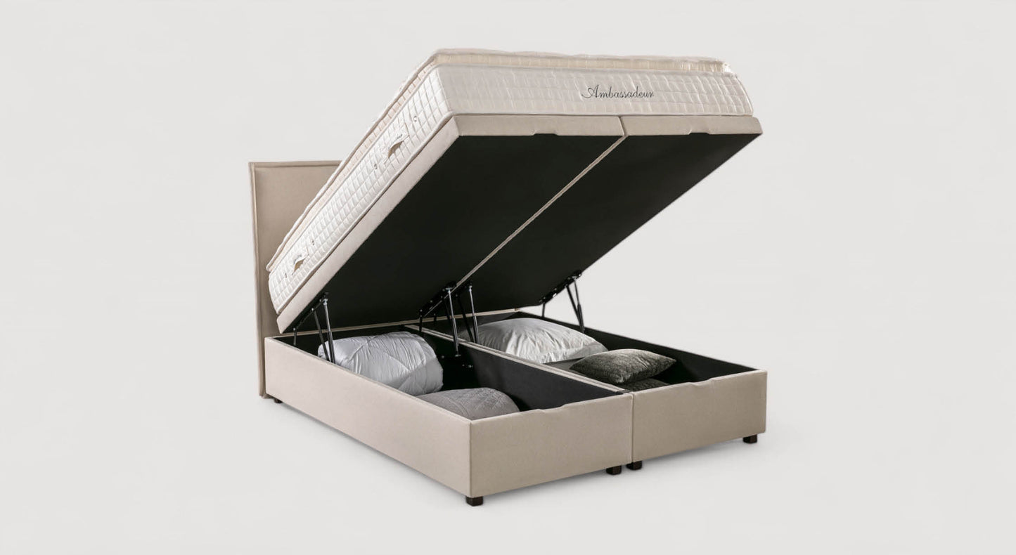 Lit coffre beige Ouessant Luca avec matelas relevé, révélant un espace de rangement contenant des oreillers et des couvertures