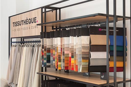 Échantillons de tissus colorés suspendus dans une boutique appelée "Tissuthèque", spécialisée dans les tissus et cuirs