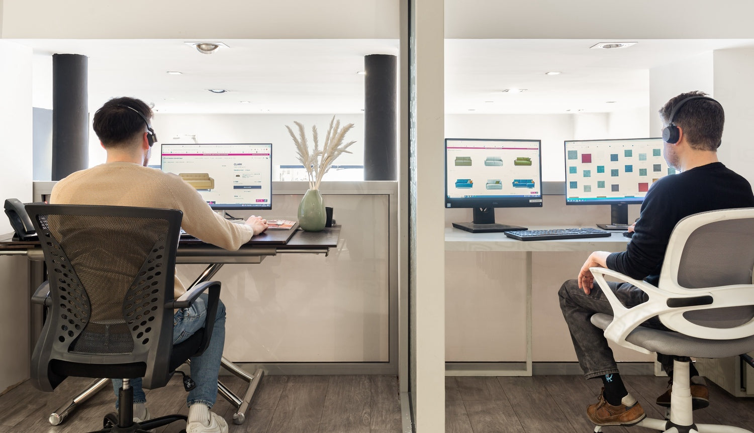 Deux personnes avec casques travaillent sur des ordinateurs affichant des sites de vente en ligne de meubles dans un bureau moderne