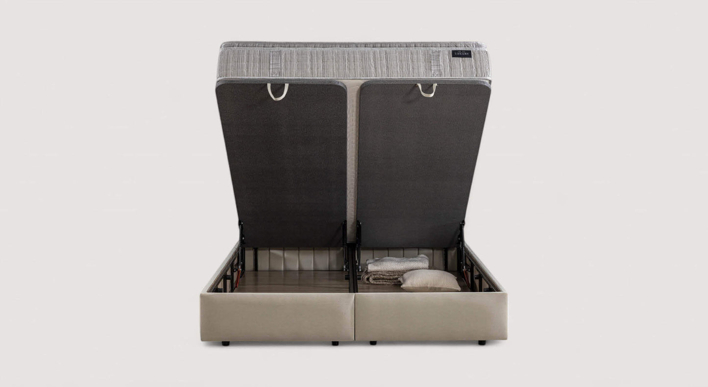 Lit coffre Amsterdam avec matelas relevé, montrant un espace de rangement contenant des couvertures et un oreiller