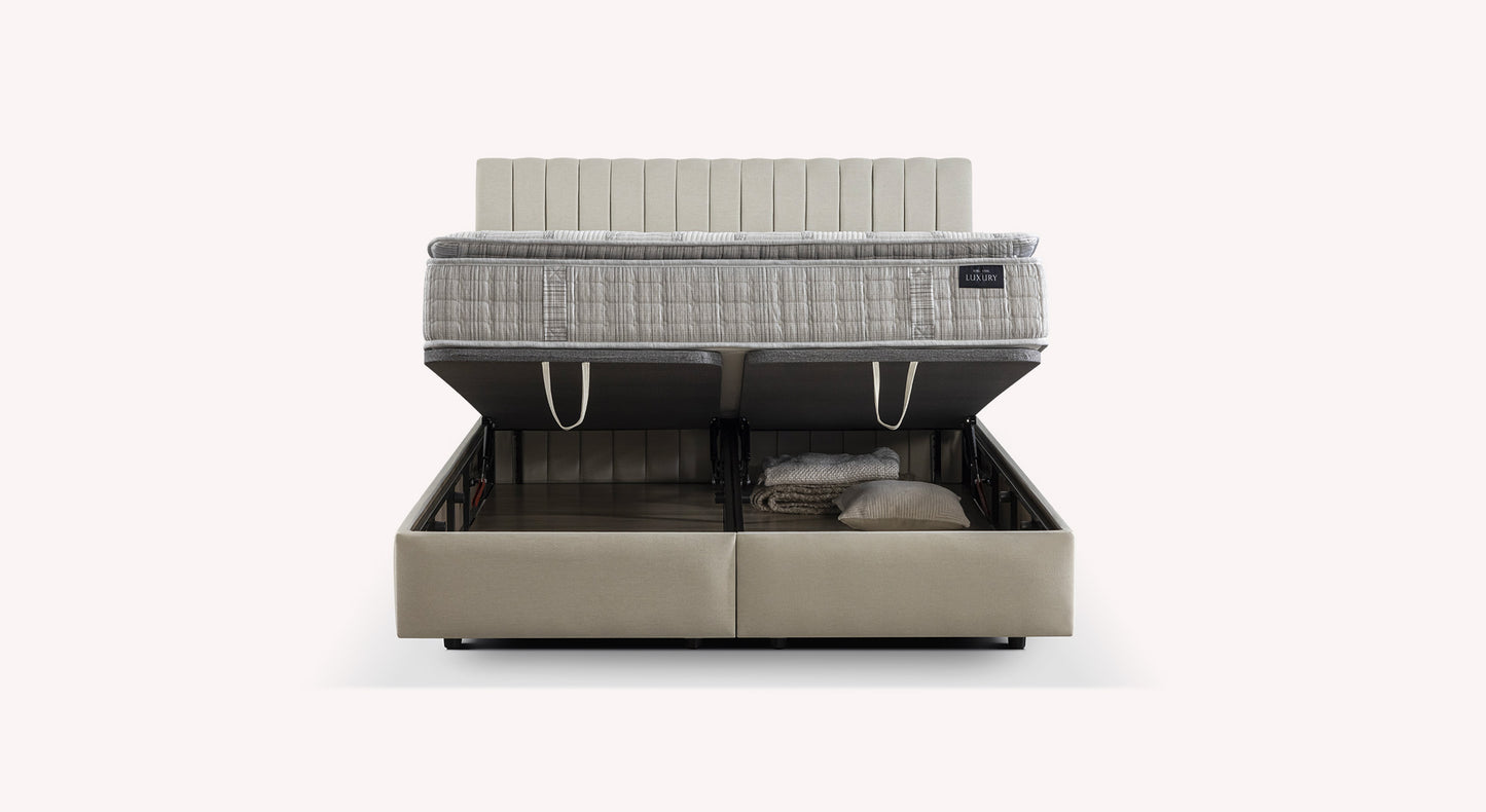 Lit coffre beige avec matelas relevé, révélant un espace de rangement contenant des couvertures et un oreiller. Modèle "Luxury"