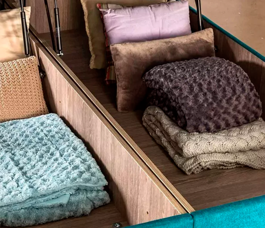 Espace de rangement d'un lit coffre avec couvertures et coussins en tissu texturé