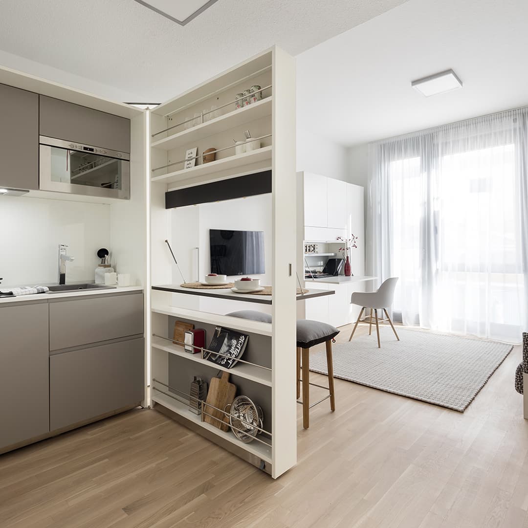 Intérieur moderne avec cuisine compacte et espace de vie lumineux, intégrant des meubles modulaires et un design épuré