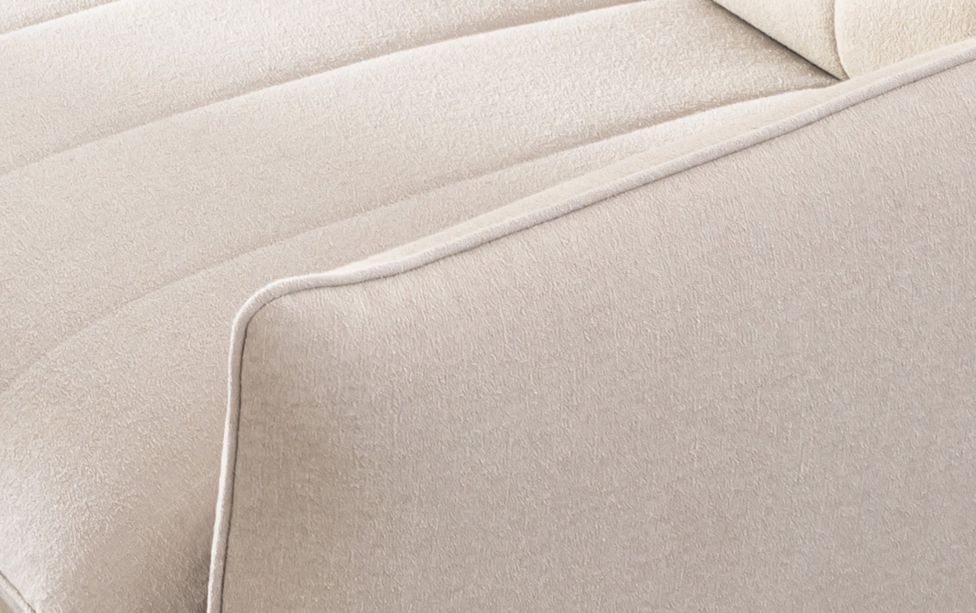 Zoom sur l'accoudoir d'un canapé convertible Dita en tissu fluf beige, montrant la revêtement douce et les coutures précises