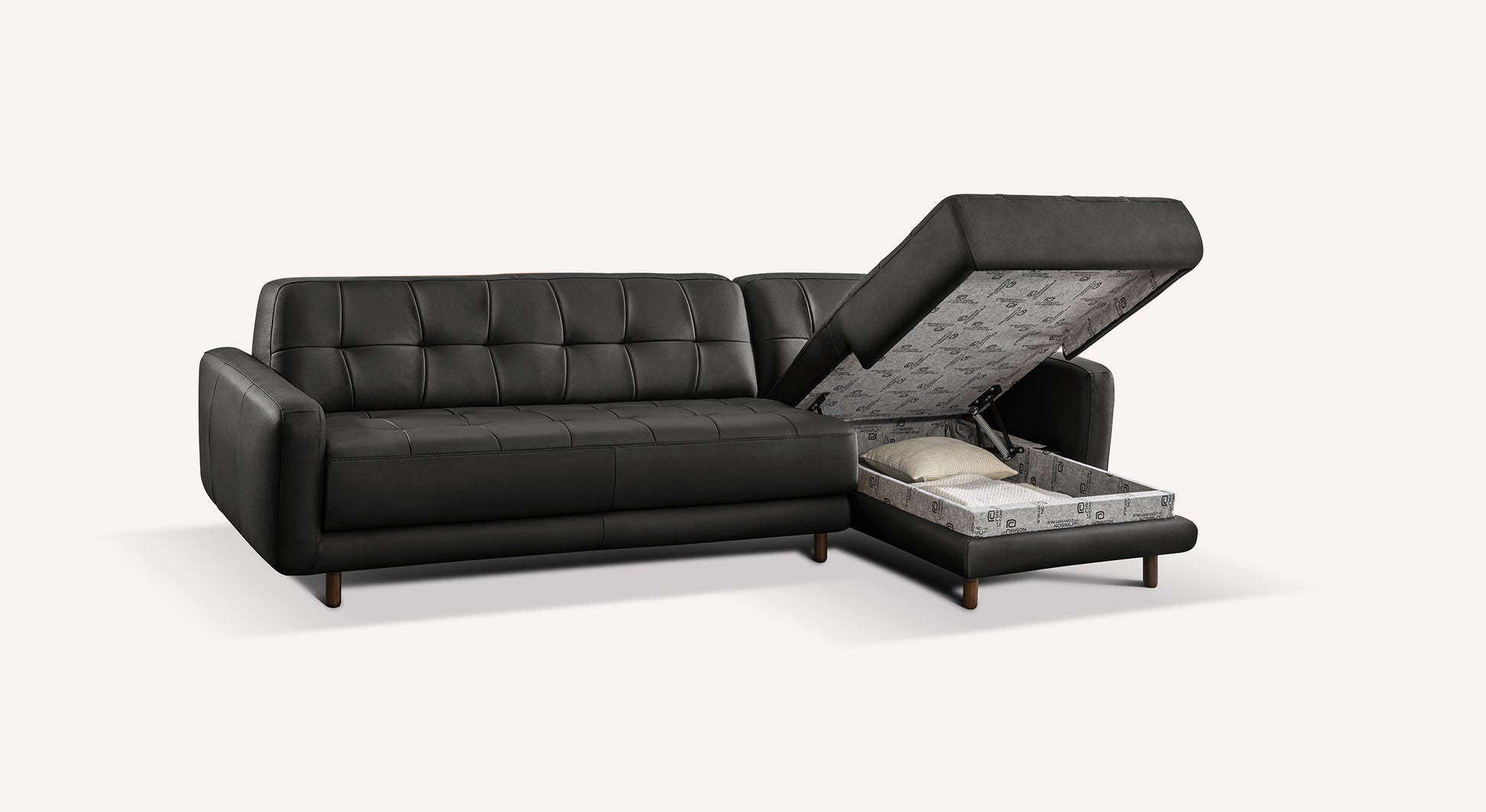 Canapé d'angle Clark en cuir noir avec rangement intégré ouvert, montrant un espace de stockage avec coussin