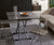 Table extensible SYDNEY Mélaminé Ancien cendré avec plateau en bois gris et pieds métalliques, aménagée dans un salon moderne avec chaises pliantes et canapé beige.