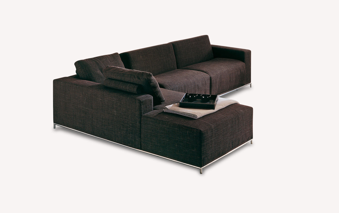 Canapé convertible en tissu marron avec accoudoirs, coussins et une couverture pliée sur l'assise