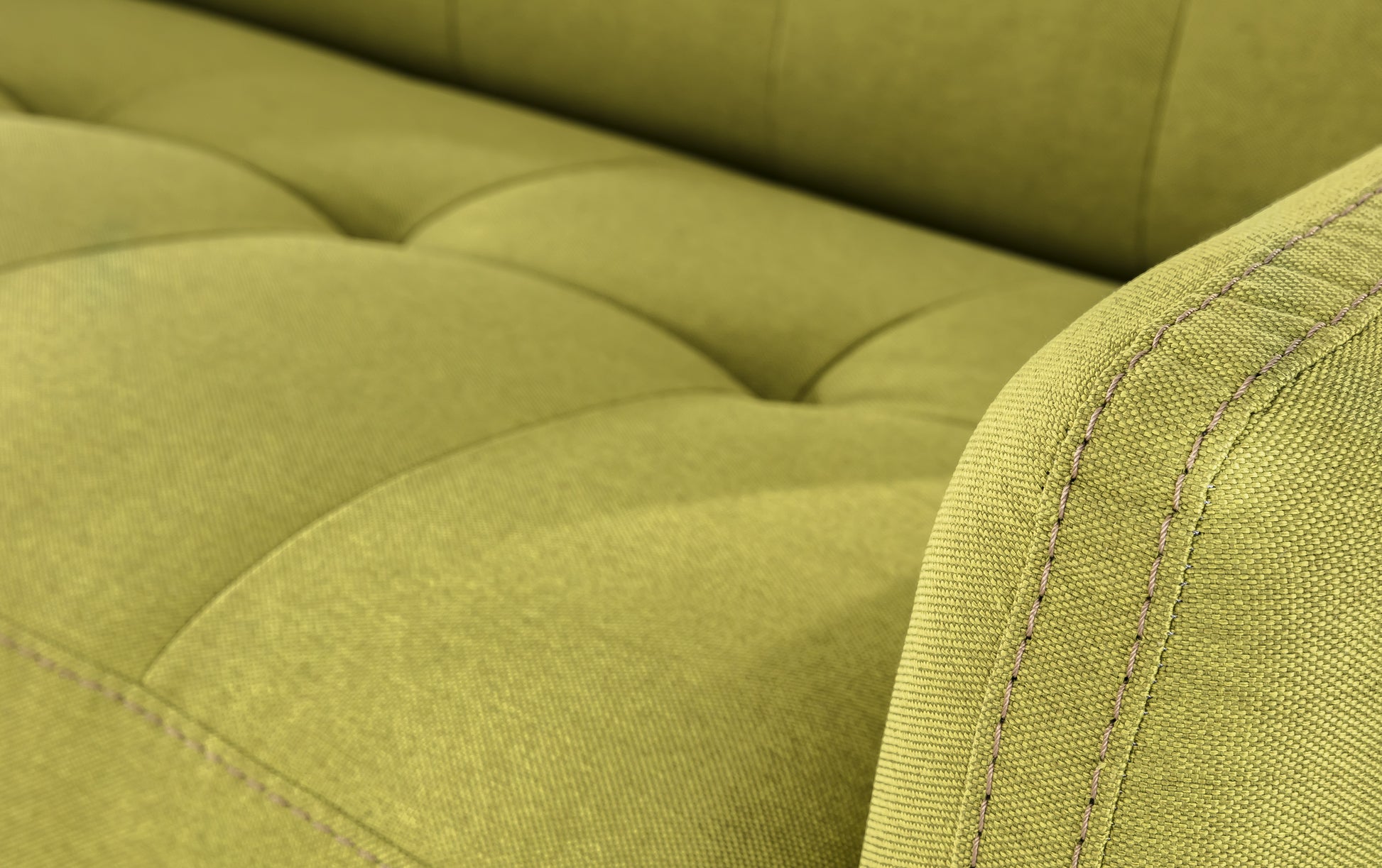 Gros plan sur l'accoudoir d'un canapé convertible en tissu vert Austin Luna, avec des coutures visibles et un rembourrage matelassé