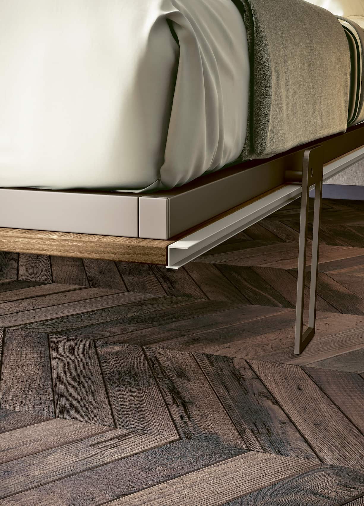 Détail d’un pied en métal et du cadre d’un canapé convertible LUCY DUO +50 coloris & matériaux sur un sol en parquet foncé, mettant en valeur la qualité des finitions.