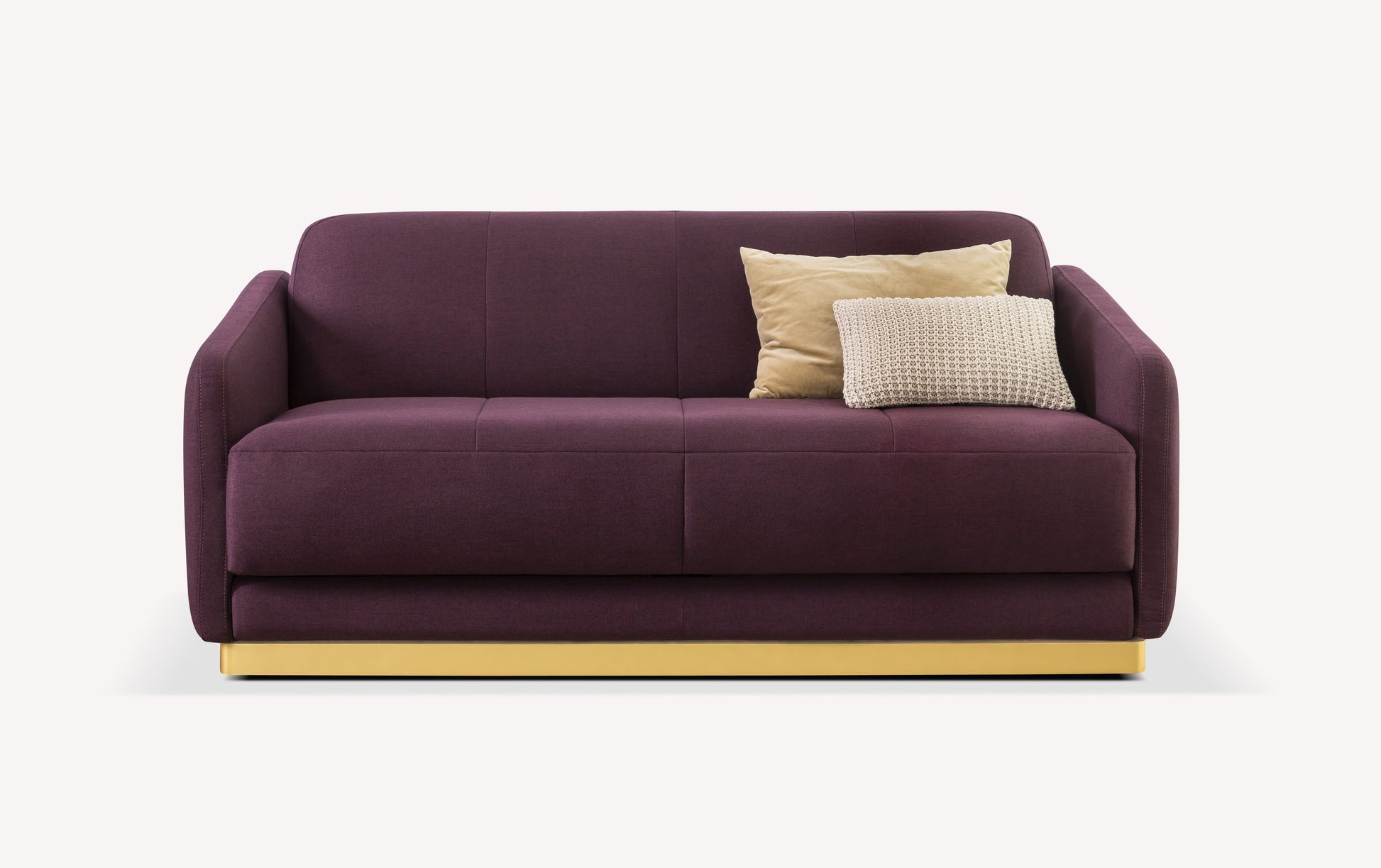 Canapé convertible en tissu violet avec base dorée, accompagné de deux coussins beiges