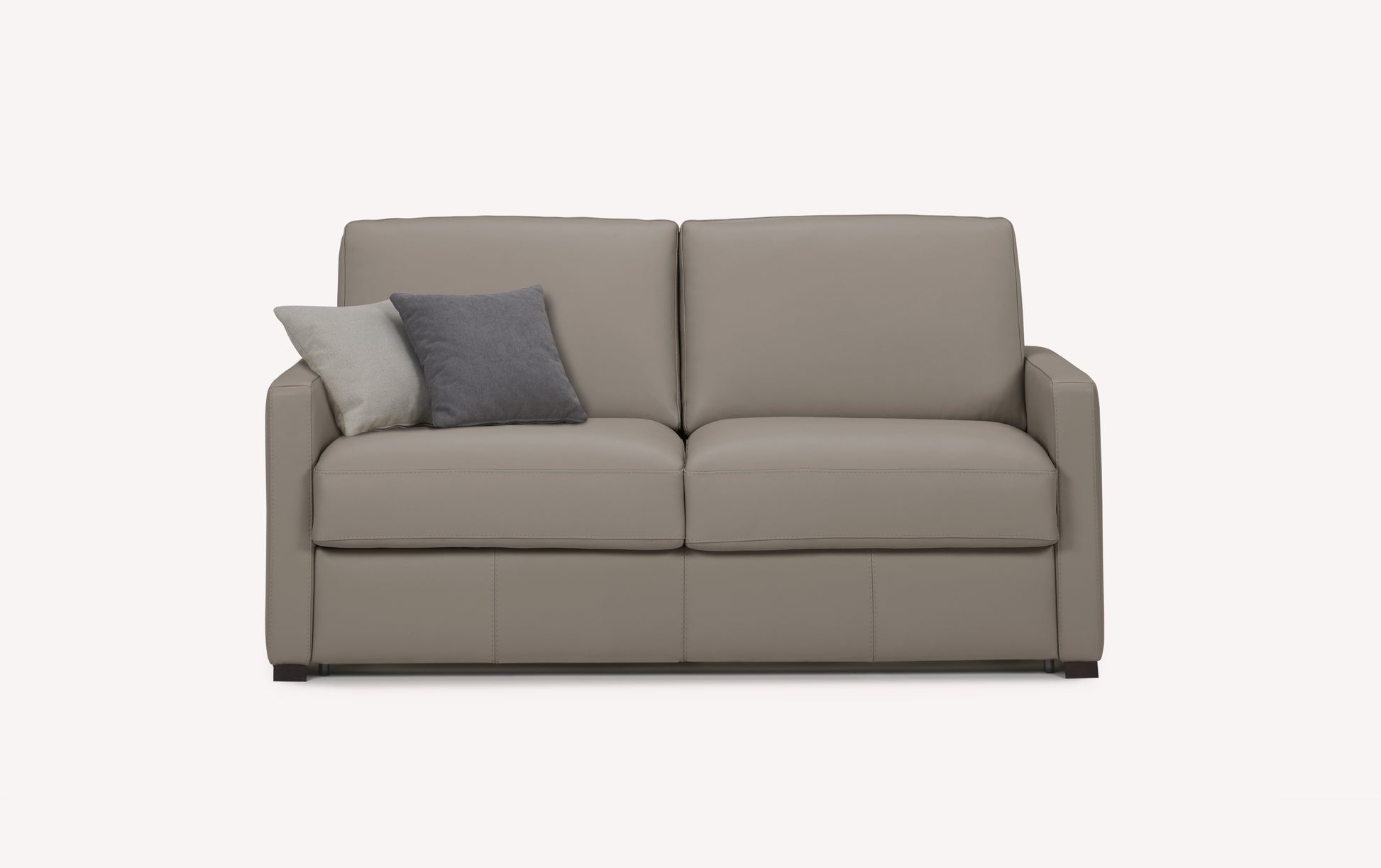 Canapé convertible en cuir gris souris avec deux coussins, un gris et un beige, sur fond blanc