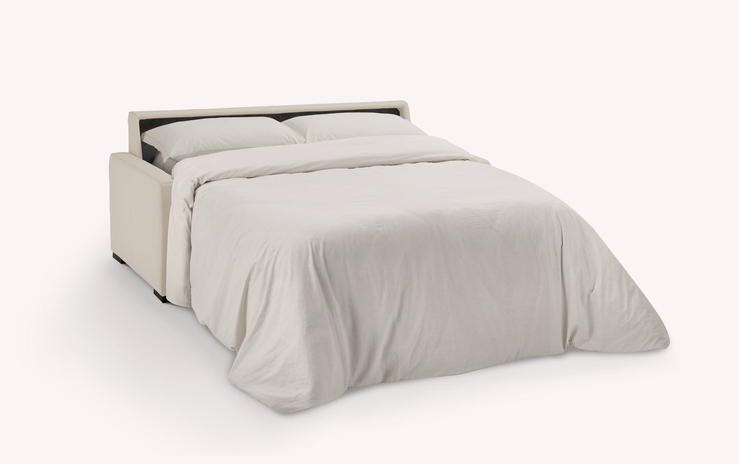 Canapé convertible en cuir luxueux, coloris avoine, ouvert en position lit avec draps blancs