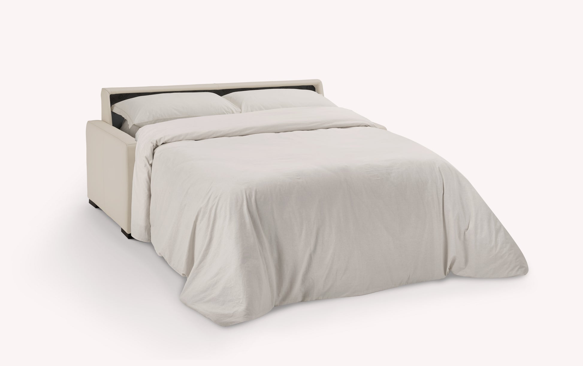 Canapé convertible en cuir luxueux, coloris avoine, ouvert en position lit avec draps blancs