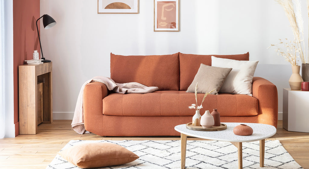 Canapé convertible Stella en tissu terracotta, ambiance chaleureuse avec coussins assortis, table basse et décoration moderne
