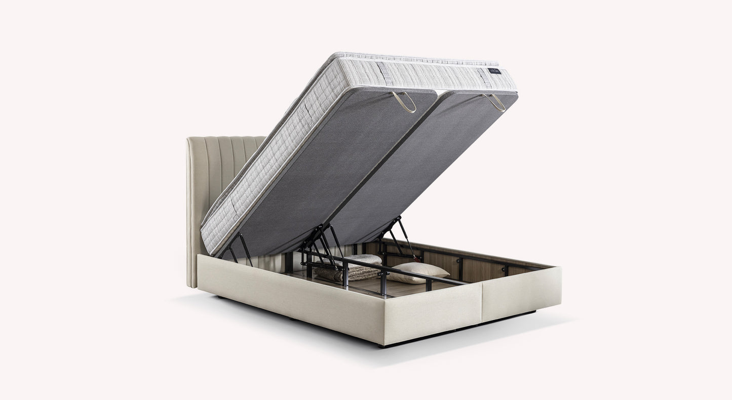 Lit coffre Amsterdam beige avec matelas relevé, révélant un espace de rangement contenant des oreillers et une couverture