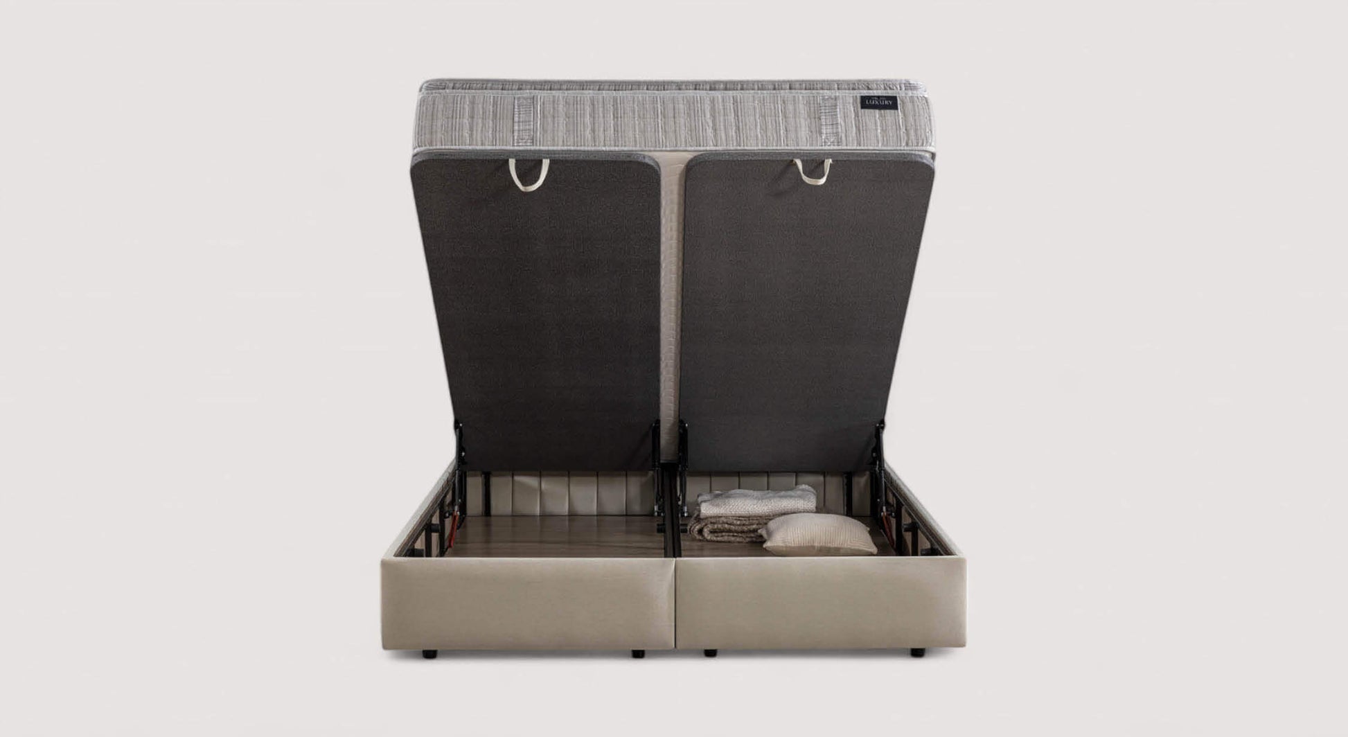 Lit coffre Amsterdam avec matelas relevé, montrant un espace de rangement contenant des couvertures et un oreiller