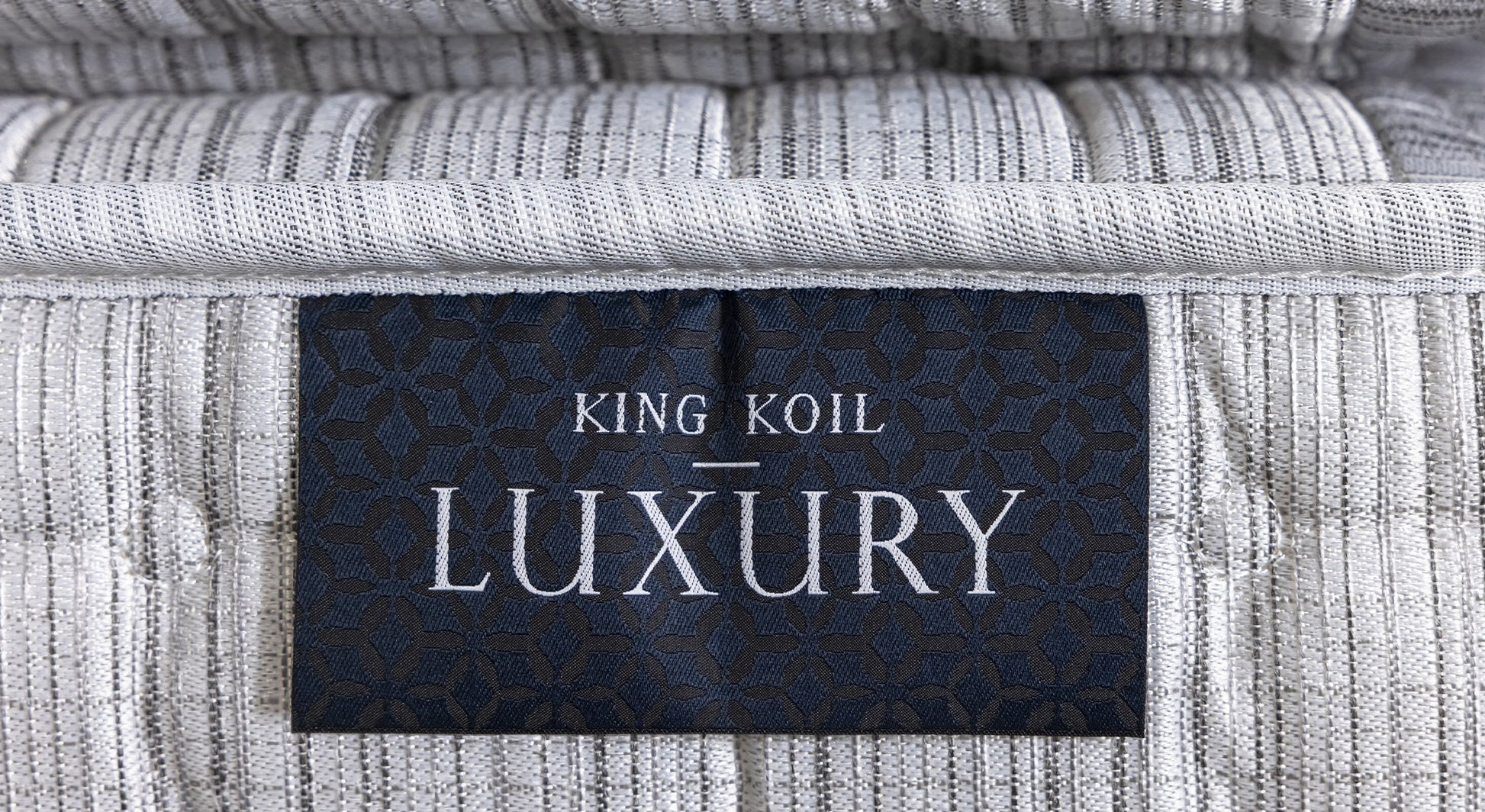 Étiquette "King Koil Luxury" sur un matelas texturé gris, évoquant le confort et l'élégance