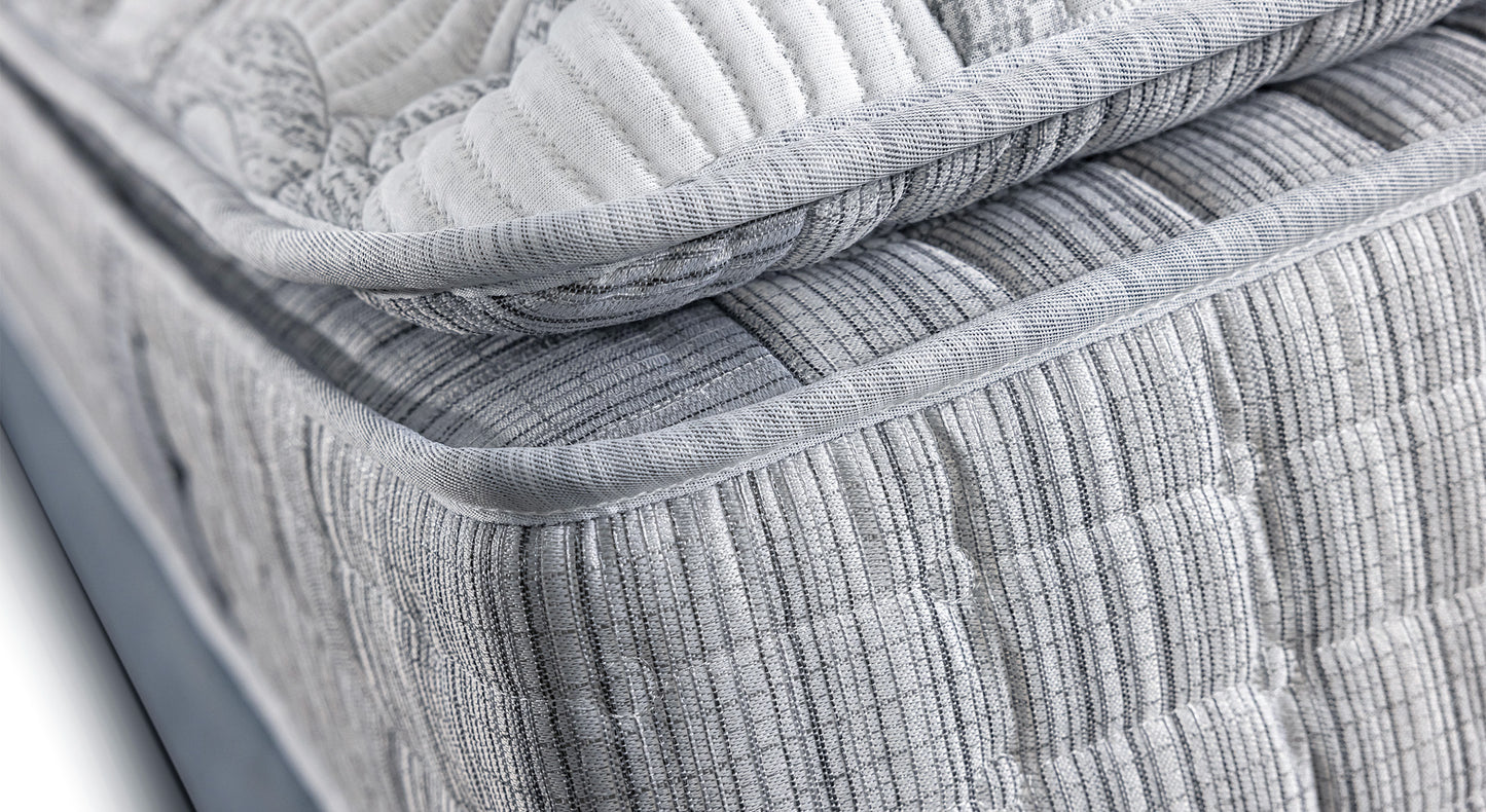 Gros plan sur le coin d'un matelas gris texturé, évoquant un produit de literie de la collection Amsterdam Florence