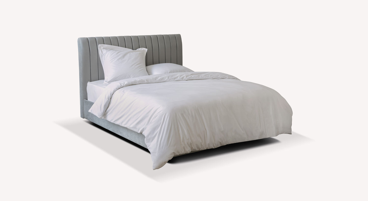 Lit gris avec tête de lit capitonnée, draps blancs, style moderne. Packshot pour Wedpack Amsterdam