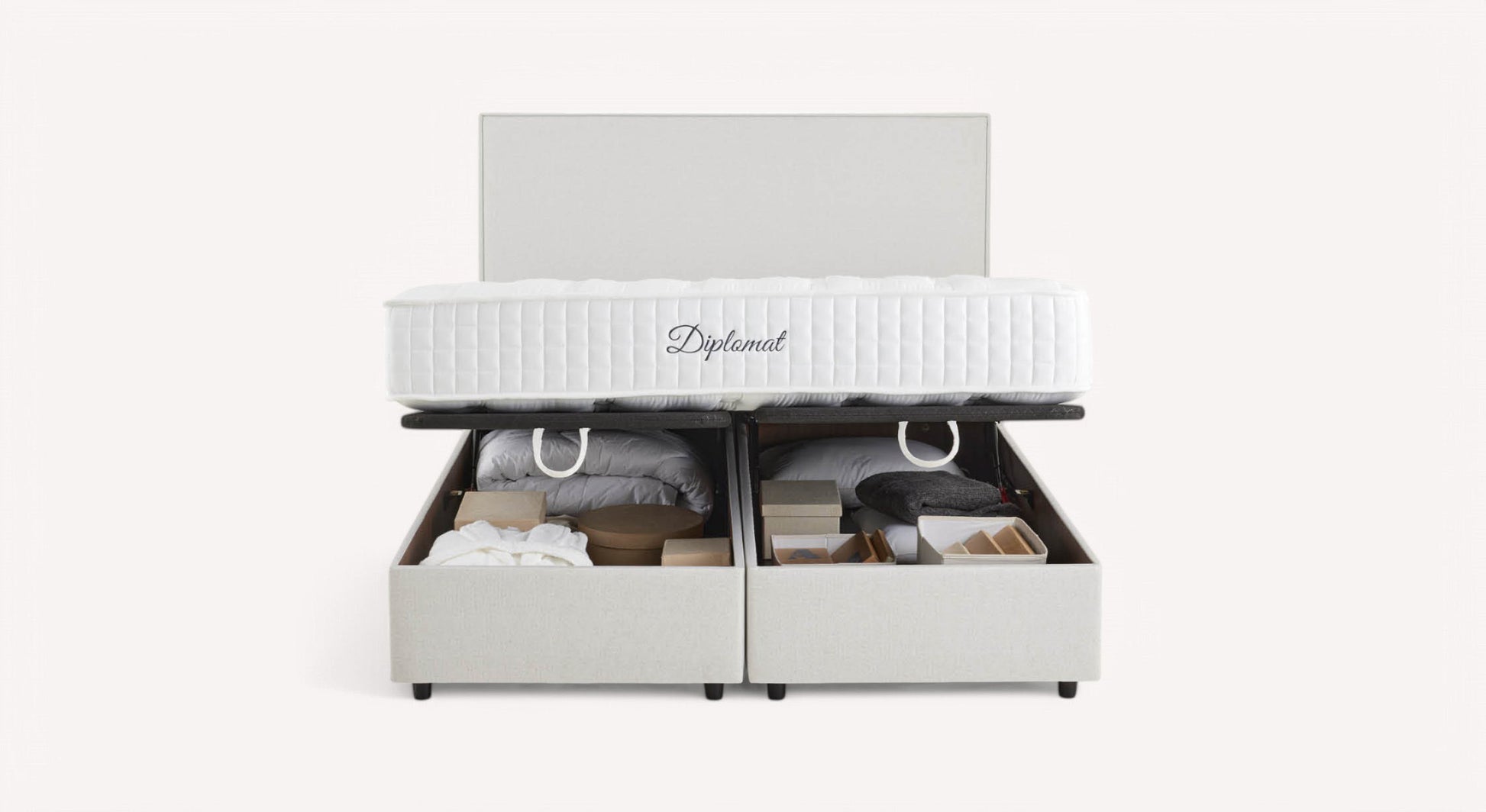 Lit coffre blanc avec matelas "Diplomat", ouvert pour révéler des rangements contenant des couvertures et des boîtes