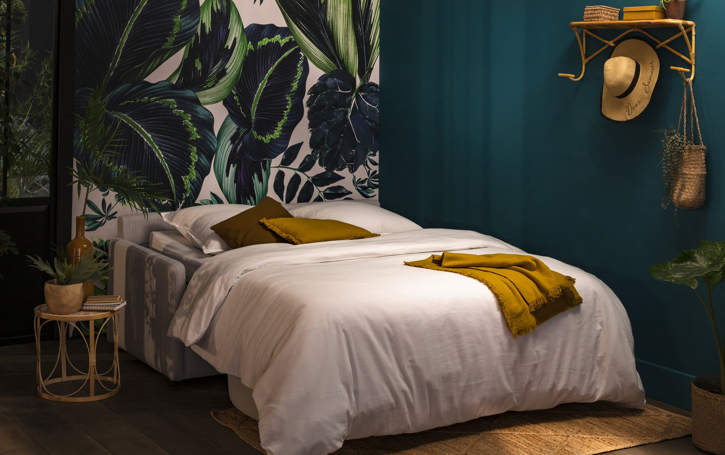 Canapé convertible en tissu blanc dans une chambre à l'ambiance nocturne, décorée de motifs végétaux et d'accessoires naturels
